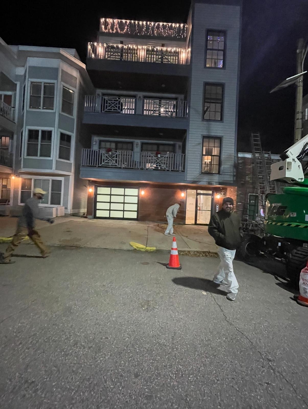 Residential facade and balconies illuminated at night, with the construction team outside