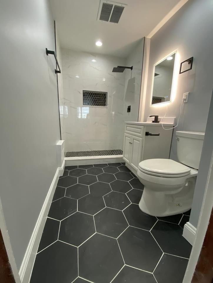Modern walk-in shower with black hexagon floor tile and contrasting marble walls